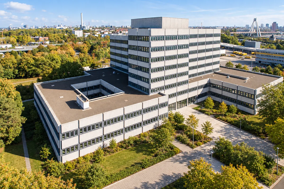 Aerial view after the retrofit: high-rise and low-rise wings with light ribbed panels and slate-gray window bands