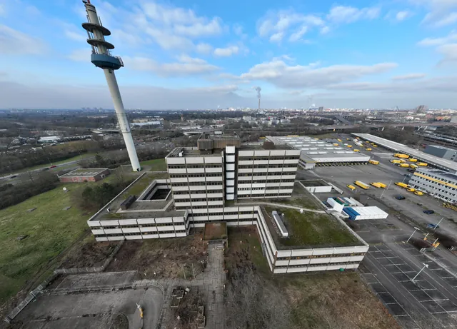 Aerial view of the complex before the retrofit: high-rise and low-rise wings with courtyard, a telecom tower on the left