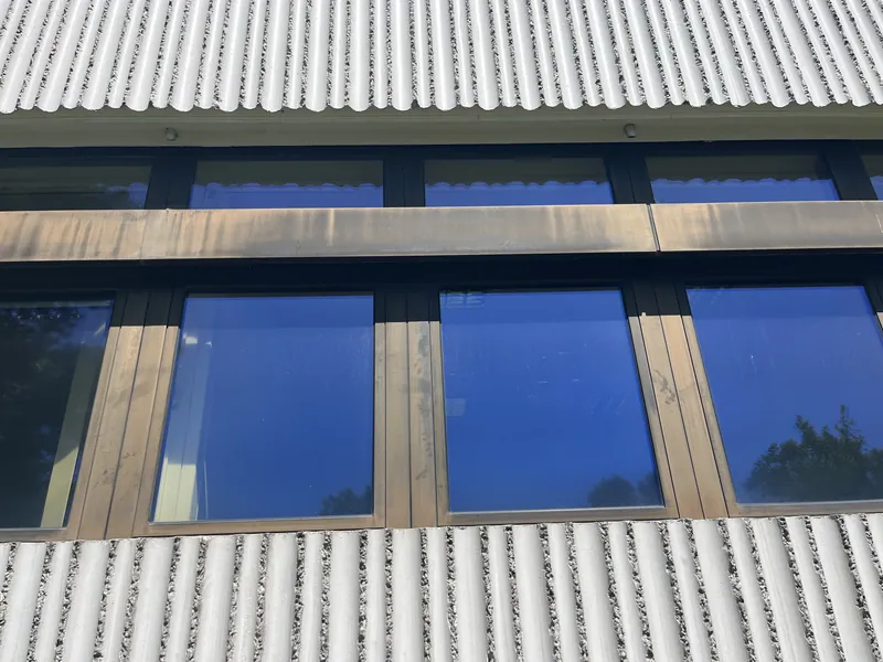 Close-up of the old aluminum frames: weathered bronze-colored profiles between the concrete panels