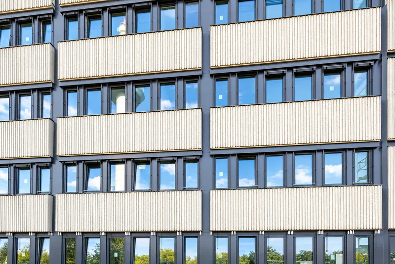 Close-up of the facade: light ribbed panels with slate-gray window bands in between